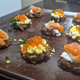 Latkes on a board with smoked salmon, hard boiled egg, row, chives, and creme fraiche.